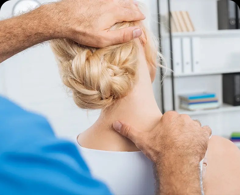 A clinician's hands supporting a patient's neck and jaw during a cervical adjustment