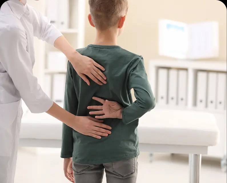 A clinician checking a child's spine and posture with both hands